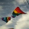 two rainbow flags with sky in background
