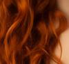 Waves of auburn hair over pale skin
